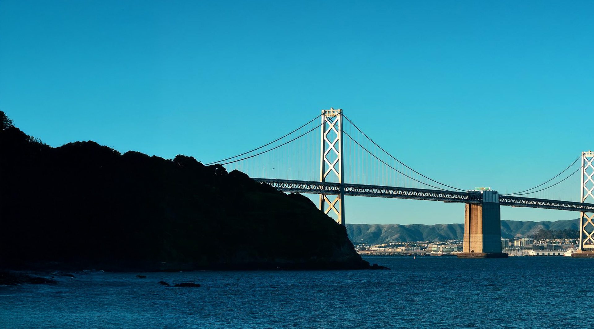 a bridge over water with a city in the background